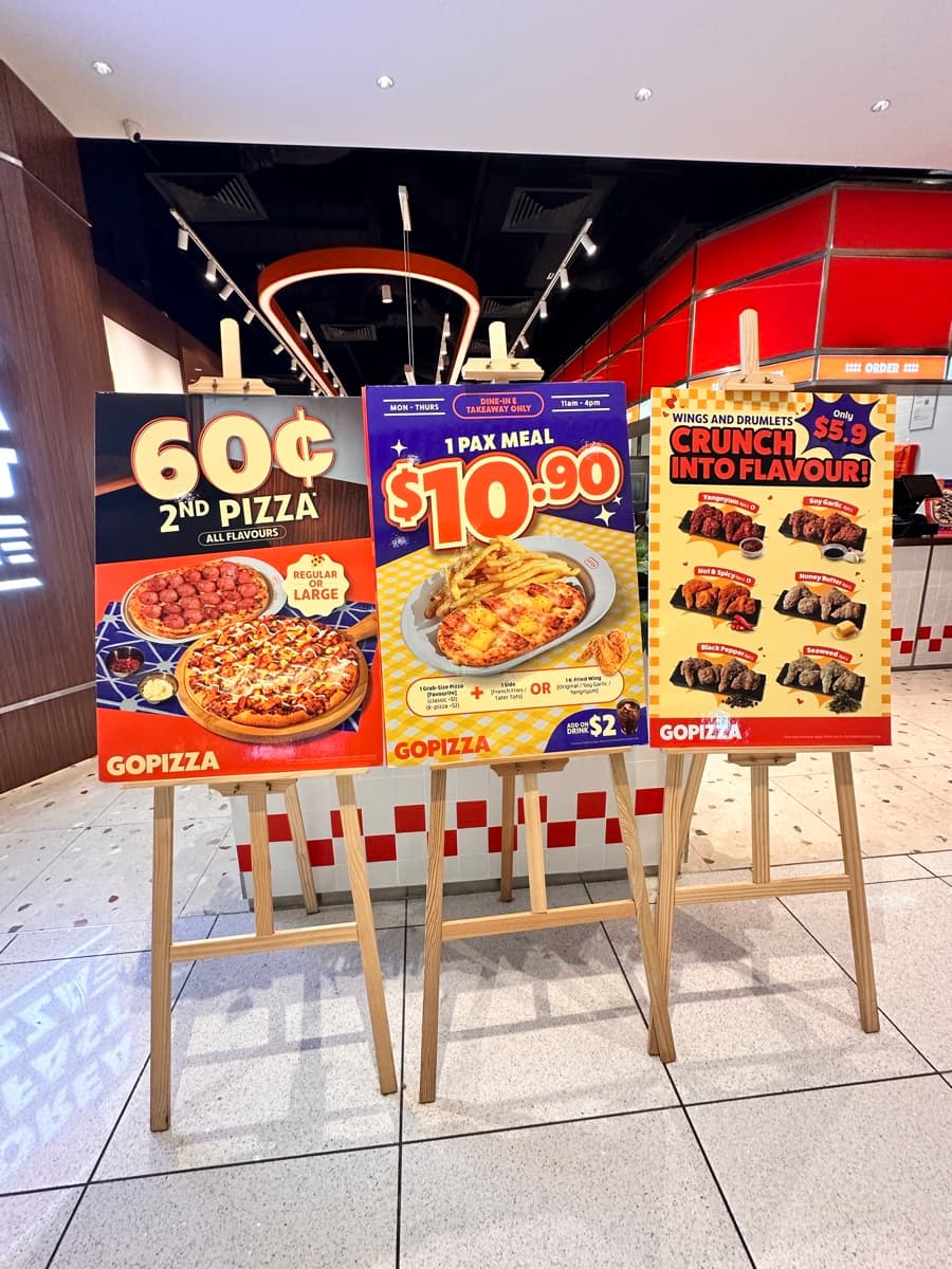 GoPizza promo standees, closer angle showing all three offers — 60¢ 2nd Pizza, $10.90 1-Pax Meal, and $5.90 Crunch — at the Suntec City storefront entrance