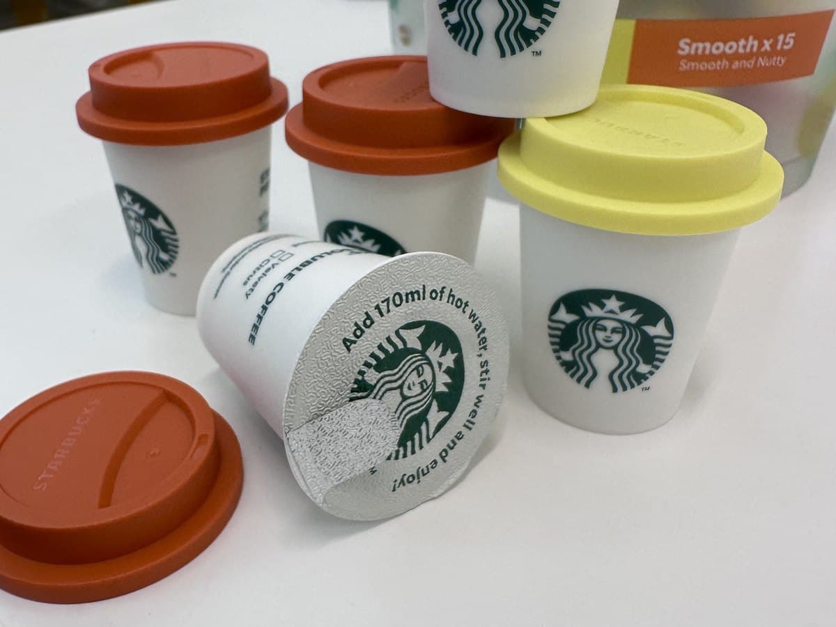 Starbucks Premium Soluble Coffee 迷你杯取下硅胶盖 — 其中一颗露出可撕封膜,上面印着「Add 170ml of hot water, stir well and enjoy」。