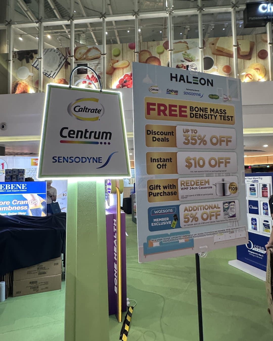 A Haleon health booth signboard listing a free bone-mass density test, up to 35% off, $10 instant off, a gift with purchase and an extra 5% off for Watsons members, with Caltrate, Centrum and Sensodyne branding.