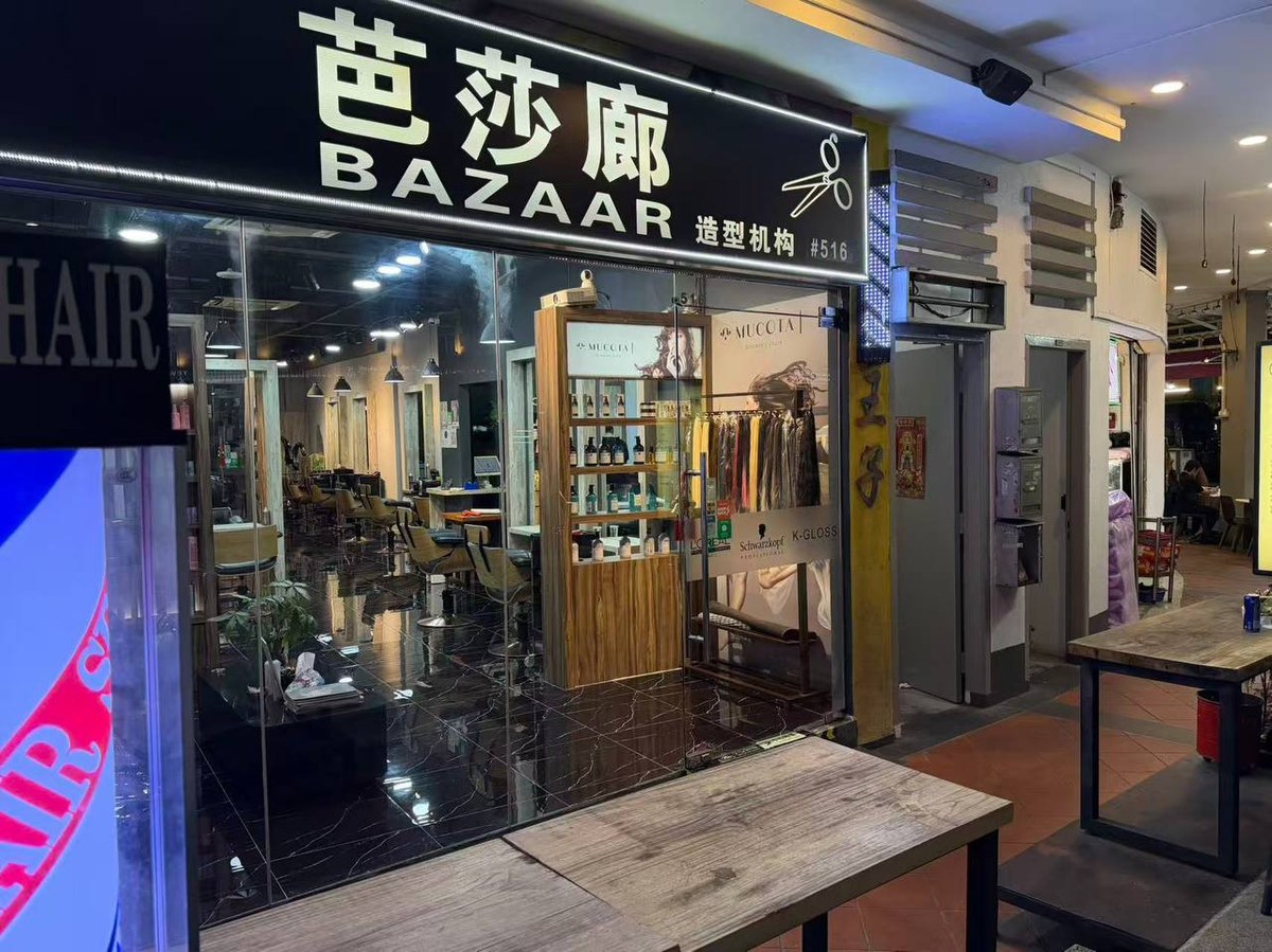 Bazaar Hair Salon's lit signboard and glass storefront at night on Geylang Road.